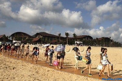 美女模特在酒店海滨沙滩上款步而行
